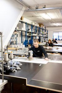 de productieruimte met grote tafels en indrukwekkende naaimachines